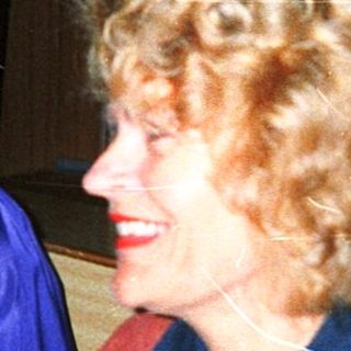 Three women smiling indoors at an event.