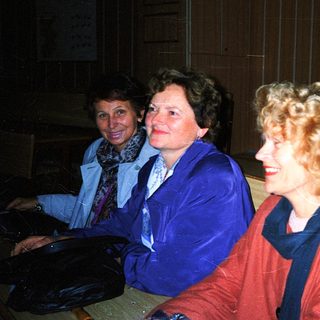 Three women smiling indoors at an event.