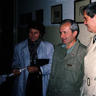 Three individuals standing indoors during an event.