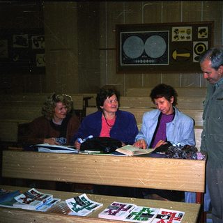 People examining documents at a table in dimly lit room.