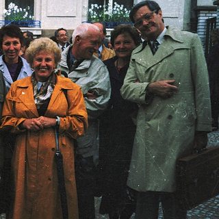 Group of people posing outdoors near historic building.