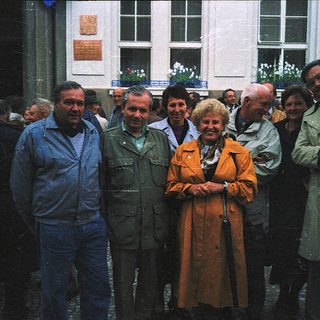 Group of people posing outdoors near historic building.
