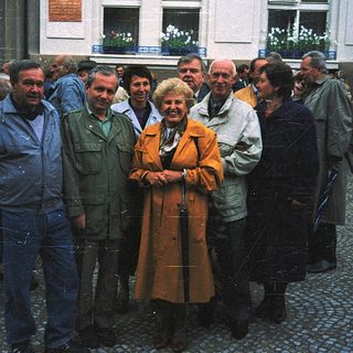 Group of people posing outdoors near historic building.