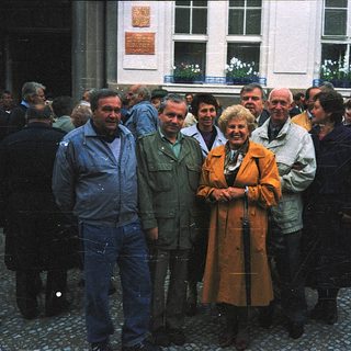 Group of people posing outdoors near historic building.