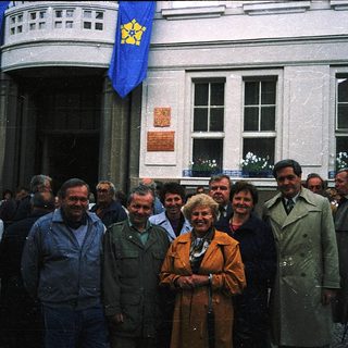 Group posing outside building with Ukrainian flags.