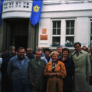 Group posing outside building with Ukrainian flags.