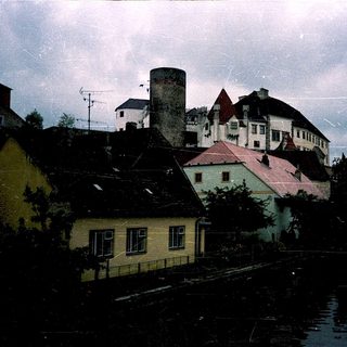 Historic European town by river with castle ruins.