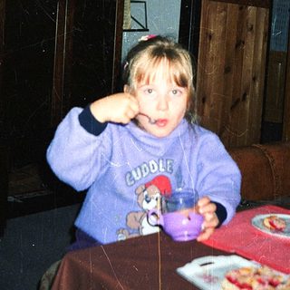Child eating pizza indoors with cup.