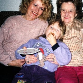 Three generations posing happily indoors together.