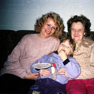 Three generations posing happily indoors together.