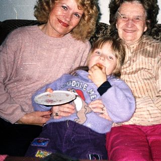 Three generations posing happily indoors with plates.