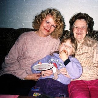 Three generations posing happily indoors with plates.