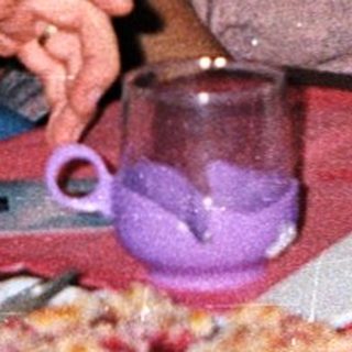 Three people sitting indoors, eating and drinking together.
