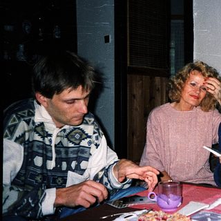 Three people sitting indoors, eating and drinking together.