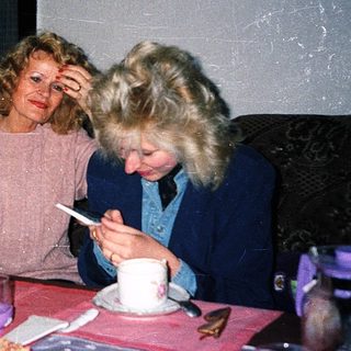 Three people sitting indoors, eating and drinking together.