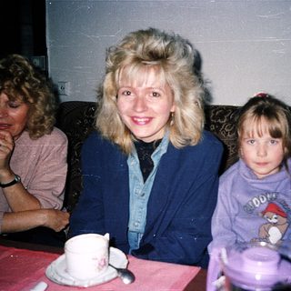 Three women sitting indoors, smiling at camera.