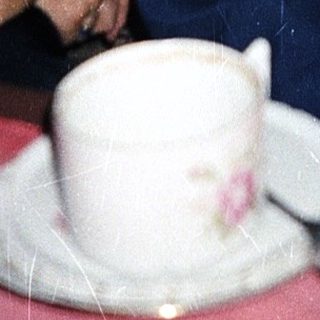 Three people sitting indoors at a table with tea.