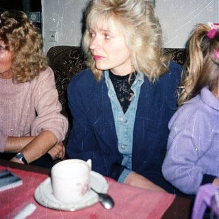 Three people sitting indoors at a table with tea.