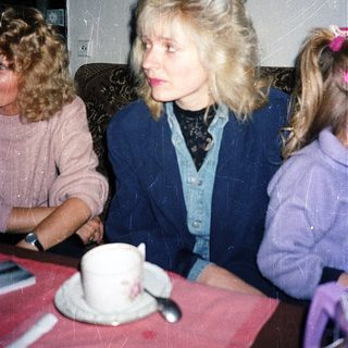 Three people sitting indoors at a table with tea.