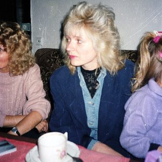 Three people sitting indoors at a table with tea.