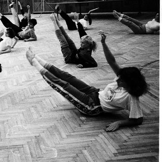 Group performing floor exercises in gymnasium.