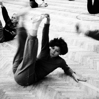 People practicing gymnastics or floor exercises indoors.