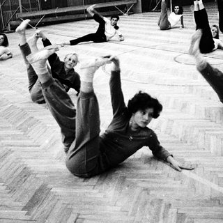Group performing floor exercises in gymnasium.