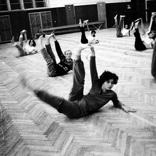 Group performing floor exercises in gymnasium.