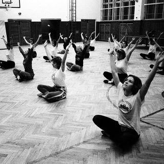 Group stretching exercise in indoor gym setting.