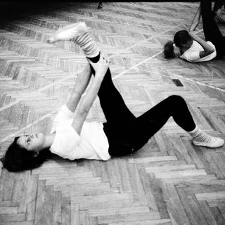 Person performing a dance move on wooden floor.