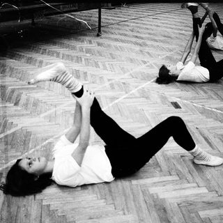 People performing floor exercises in gym.