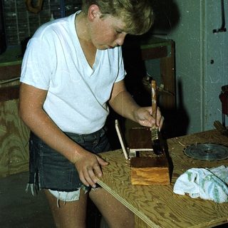 Young man using hand plane on wooden board.