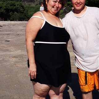 Two people posing happily on a beach.