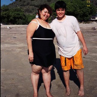 Two people posing happily on a beach.