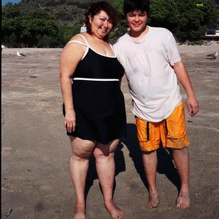 Two people posing happily on a beach.