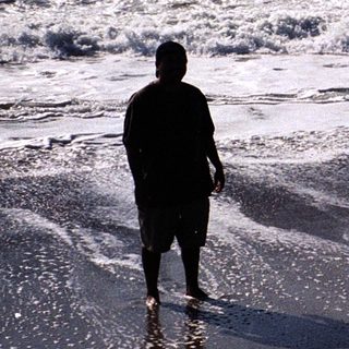 Two people standing on wet beach near waves.