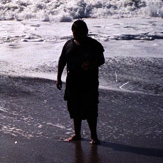 Two people standing on wet beach near waves.