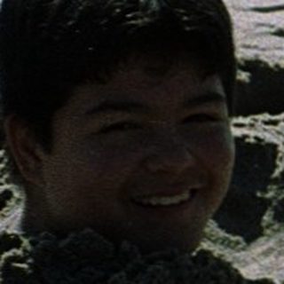 Two children playing in beach sand tunnels.