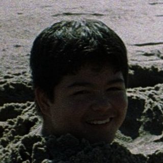 Two children playing in beach sand tunnels.