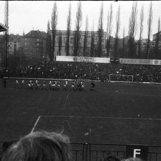 Black-and-white football match with packed stadium.