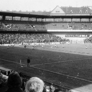 Black-and-white stadium football match in progress.