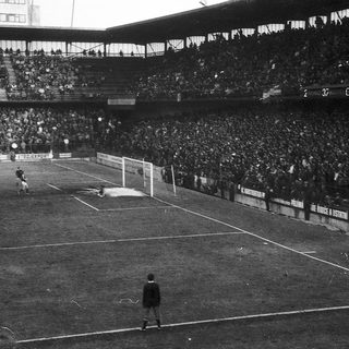 Black-and-white soccer match with packed stadium.