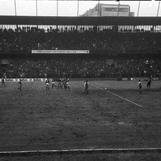 Football match in crowded stadium.