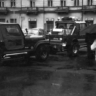 Traffic jam with vintage Jeeps and cars in wet urban area.