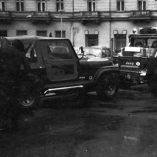 Traffic jam with vintage Jeeps and cars in wet urban area.