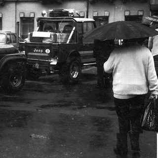 Traffic jam with vintage Jeeps and cars in wet urban area.