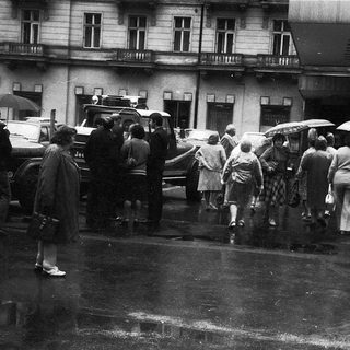 People walking in rain with umbrellas, vintage street scene.