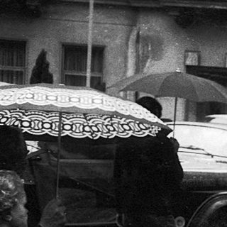 People walking in rain with umbrellas, vintage street scene.