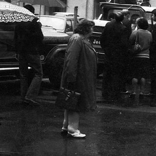 People walking in rain with umbrellas, vintage street scene.