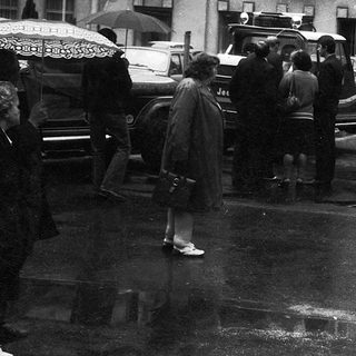 People walking in rain with umbrellas, vintage street scene.